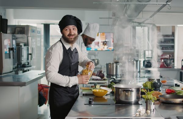 Authentic cook doing cooking show lesson on camera in kitchen, preparing gourmet meal with culinary recipe. Man recording dish preparations on camera for gastronomy television program.