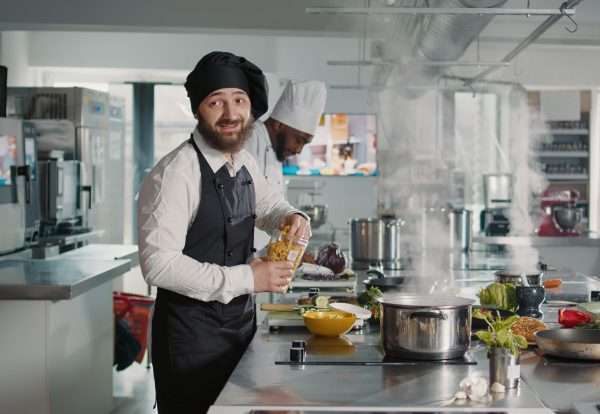 Authentic cook doing cooking show lesson on camera in kitchen, preparing gourmet meal with culinary recipe. Man recording dish preparations on camera for gastronomy television program.