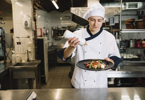 cook-pouring-sauce-big-plate-with-salad